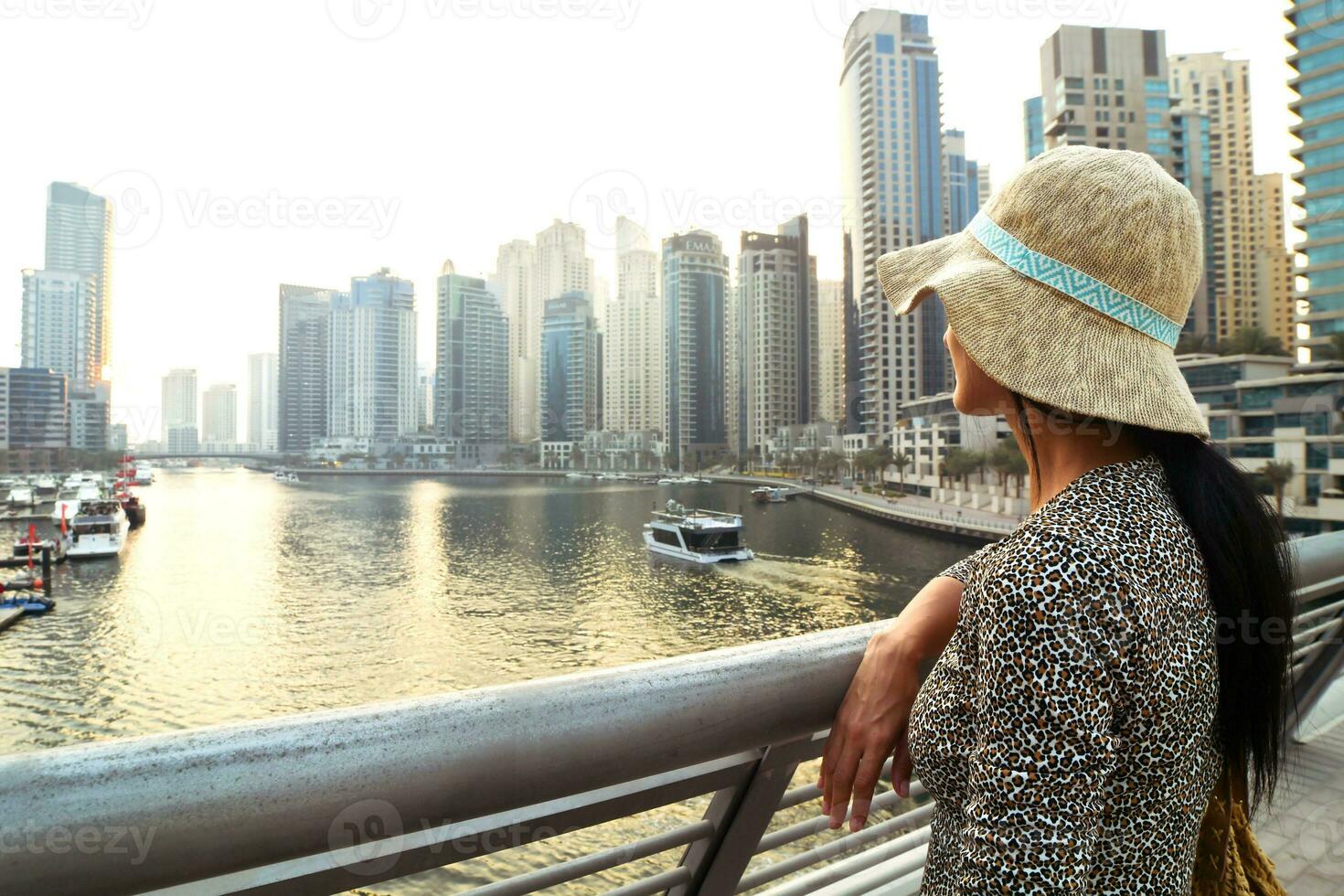 Dubai, UAE, 2022 - beautiful caucasian tourist woman in fashionable summer dress enjoy Dubai marina in United Arab Emirates. Luxury and comfortable tourism season photo