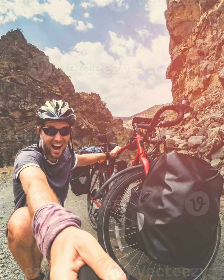 masculino caucásico loco ciclista por bicicleta tener gracioso expresión al aire libre actitud en ciclismo viaje. viaje alrededor mundo ciclista experiencia documentando foto