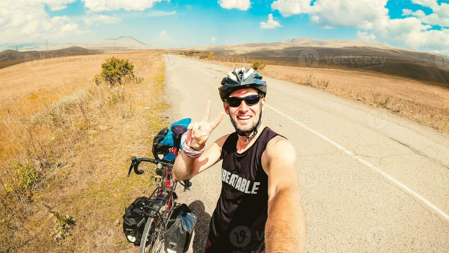 Caucasian male person stand by bicycle solo touring in tranquil countryside fully loaded with bags outdoors in summer heat show thumbs up. Creative ecological travel concept photo