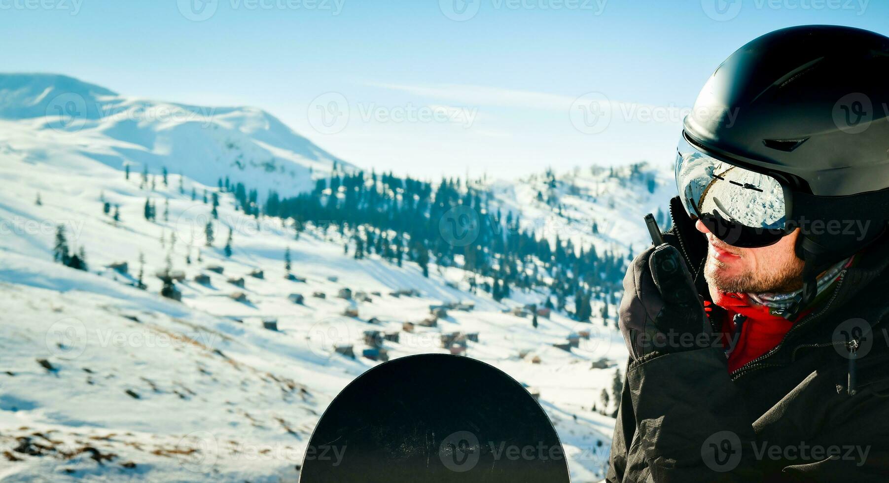 Portrait of bearded man snowboarder on walkie-talkie wear sunglasses and ski helmet for safety. Radio talk device. Emergency and safety concept photo