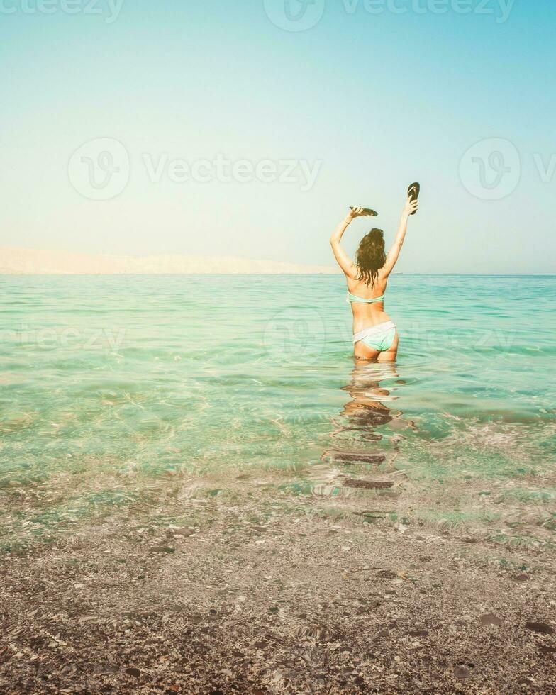 Tourist woman stand in clear turquoise water in persian gulf Mirellas island sandy white beach. Oman coastline paradise. Musandam. photo