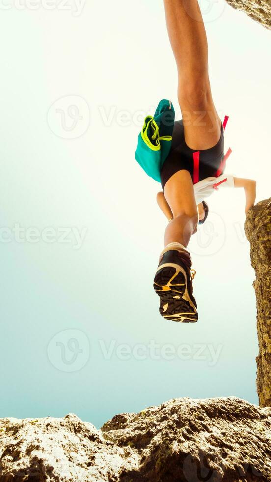 Low view female body step feet in air on hiking over rocks outdoors alone in hot sunny day outdoors. Motion blur filter. Shoe grip and footwear on climbing concept photo