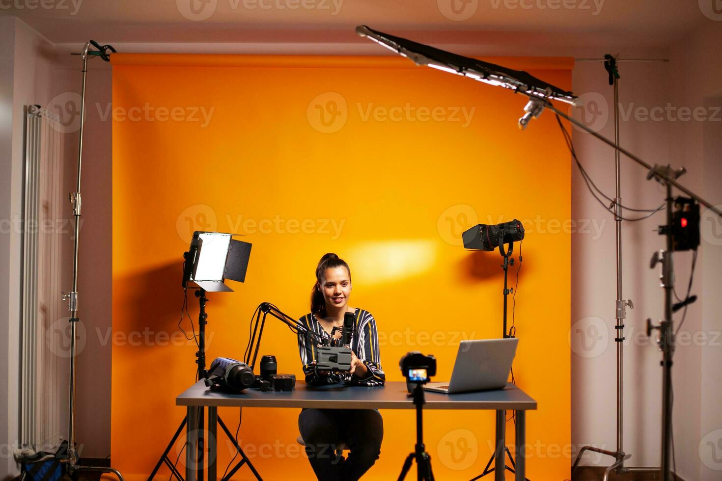 Videographer showing battery with vmount in home studio for podcast. Professional videography gear review by content creator new media star influencer on social media. photo