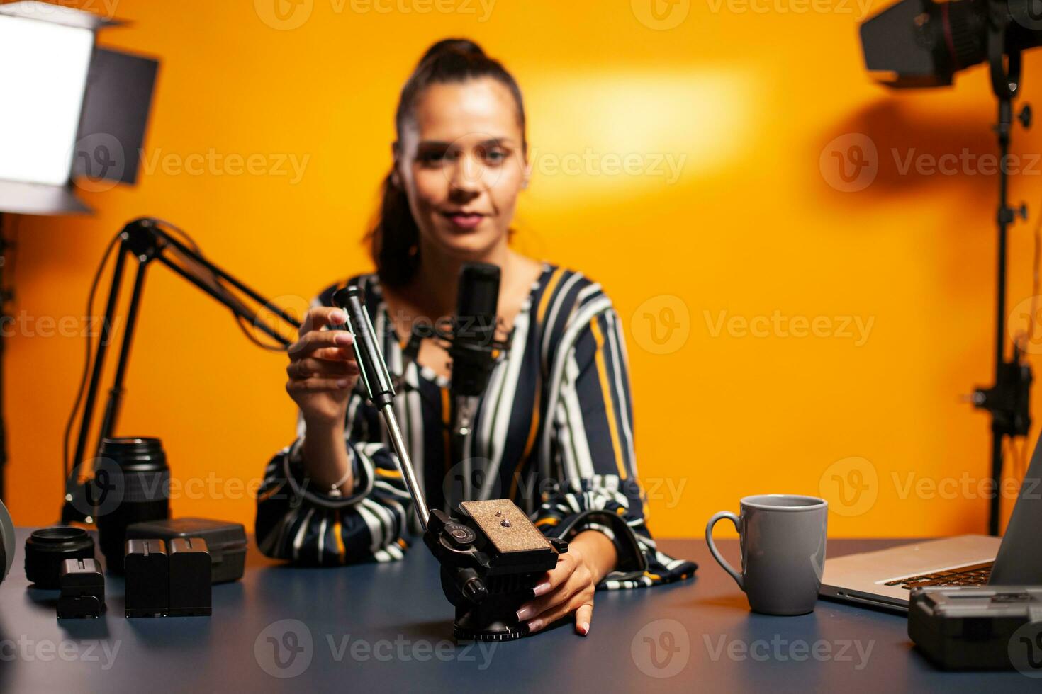 Filmmaker holding fluid head and talking baout it during podcast in home studio. Social media star making online internet content about video equipment for web subscribers and distribution, film photo
