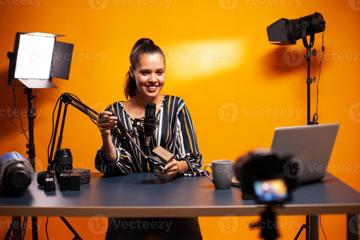 Influencer smiling into camera and recording podcast in studio. Social media star making online internet content about video equipment for web subscribers and distribution, film photo