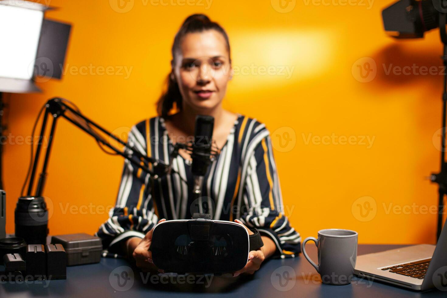 Woman holding headset while recording video blog in home studio. Video blog studio review of weareble technology with stereoscopic cyber reality, electronics gadget experience, gaming industry photo