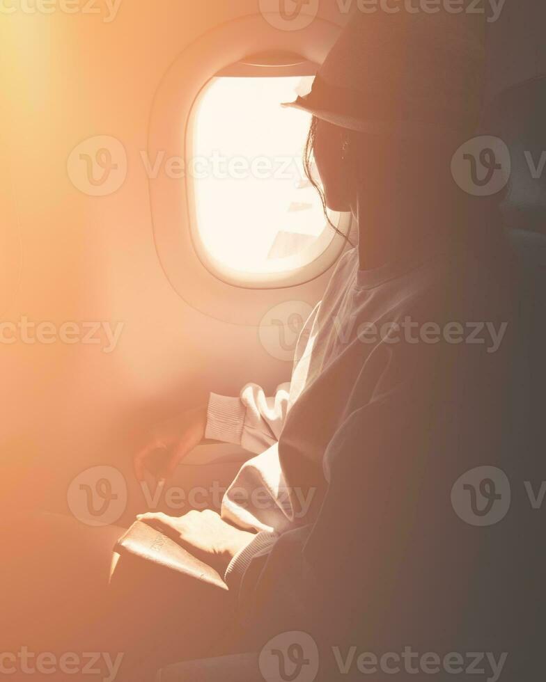 Close up silhouette of caucasian woman passenger look to window sit on chair on flying commercial airplane. Passenger on the plane restbeside the window enjoy travel hold passport photo