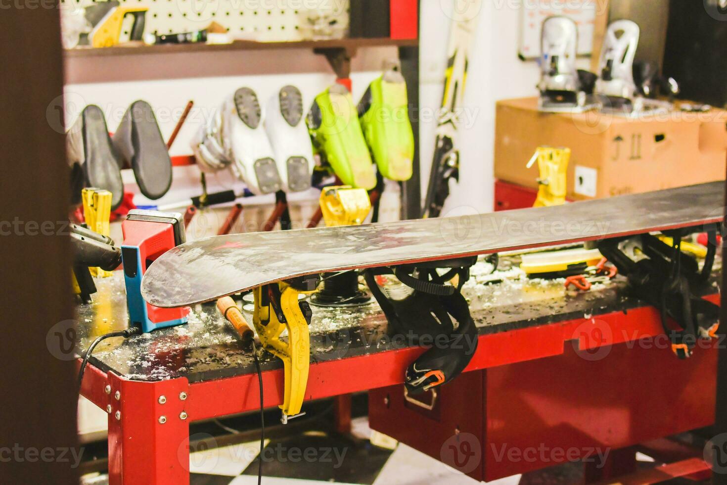 cierre el snowboard encerado en la mesa del taller de reparación. taller desordenado y espacio de trabajo en la tienda de esquí. guía paso por paso foto