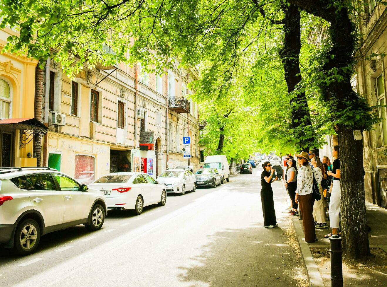 Tbilisi, Georgia, 2022 - Group of tourist stand with guide in street on free Tbilisi walking tour in sunny spring day. Sololaki hidden Tbilisi tour photo