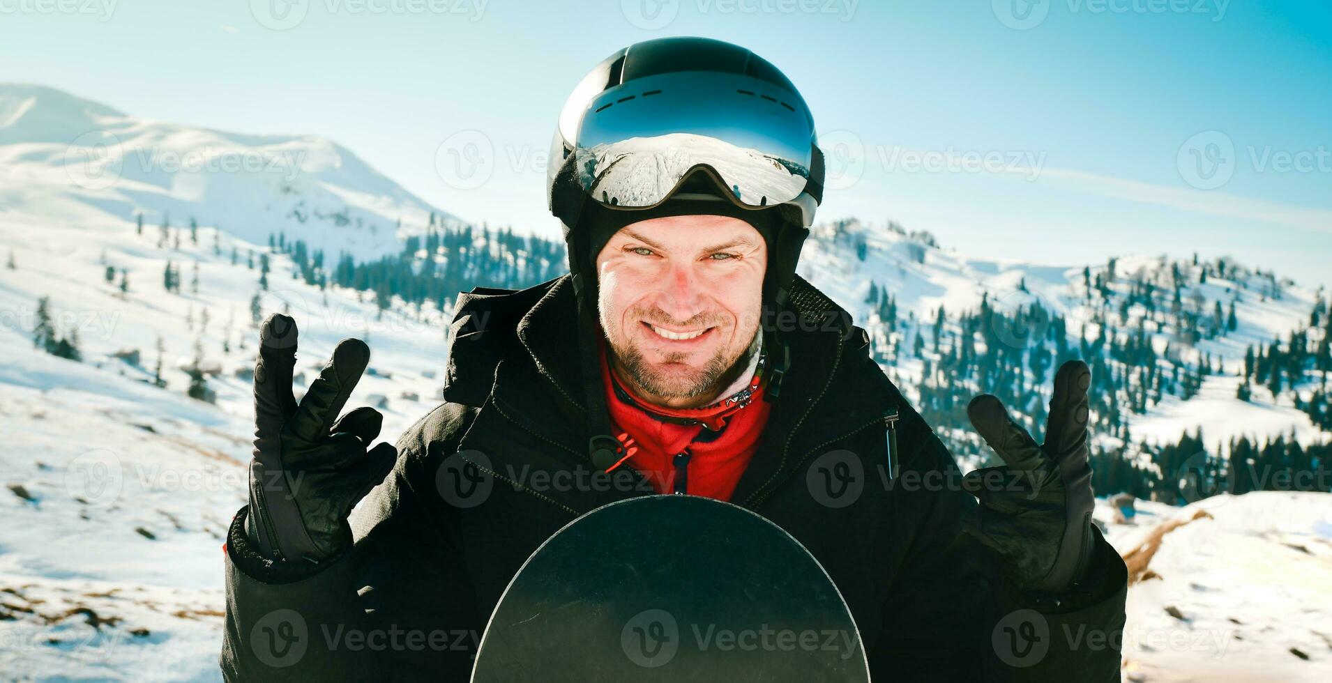 Close up portrait caucasian man with the reflection of snowed mountains, white slope and ski resort. A mountain range reflected in the ski mask. Portrait of man at the ski resort photo