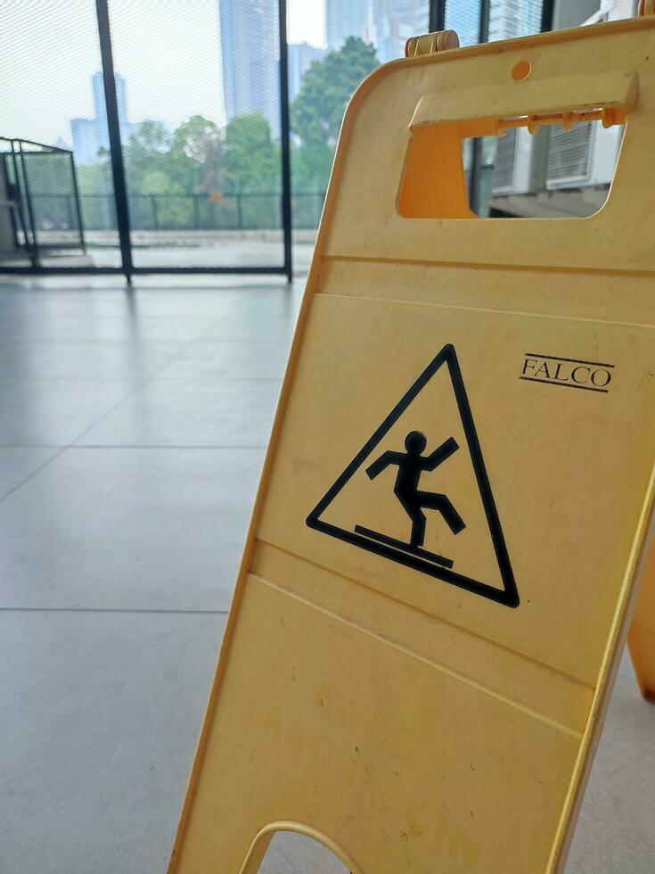 Yellow caution sign on the floor in the office building with cityscape background photo