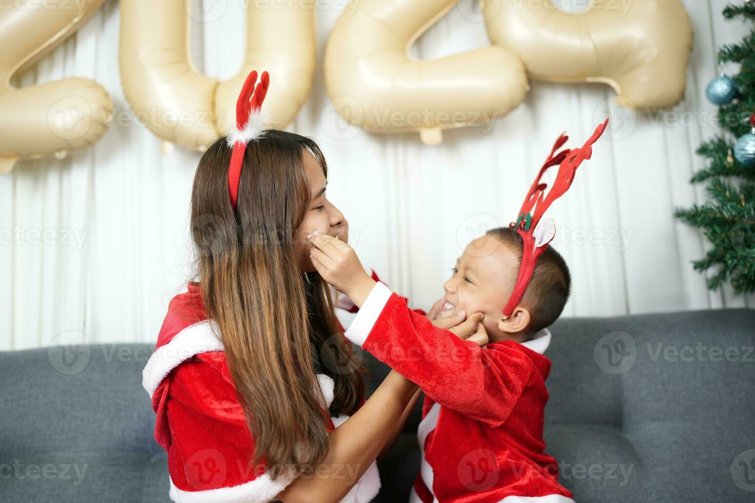 Merry Christmas 2024 concept Mother and child decorate the Christmas tree with colorful Christmas balls. photo