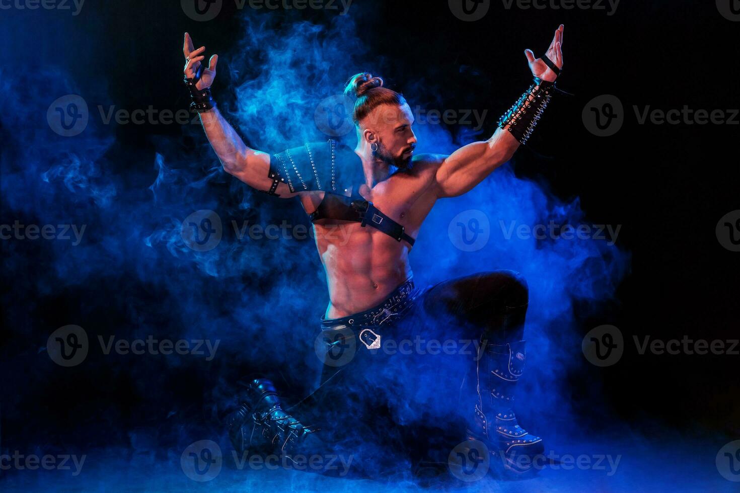 Young and muscular man performing a theatrical pose on stage. photo