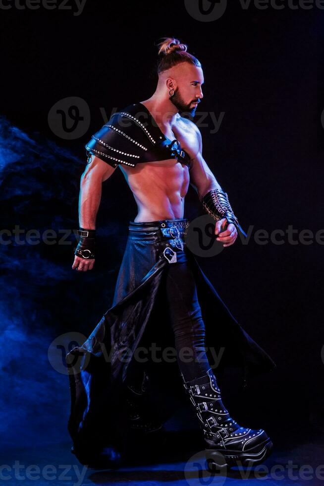 Handsome young sexy man with beautiful muscular chest in interesting costume on the scene photo