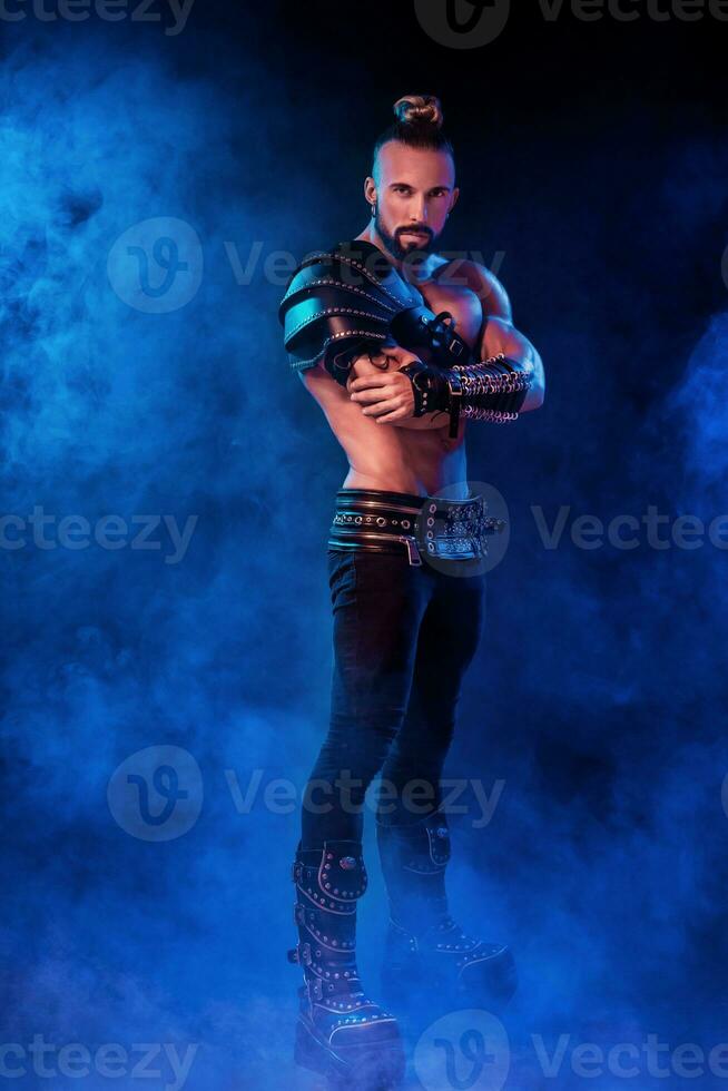 Handsome young sexy man with beautiful muscular chest in interesting costume on the scene photo