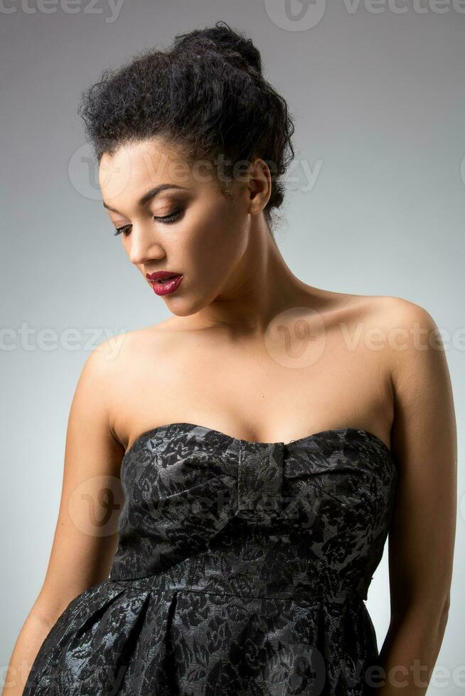 Portrait of beautiful brunette girl in the studio on a gray background in dress photo