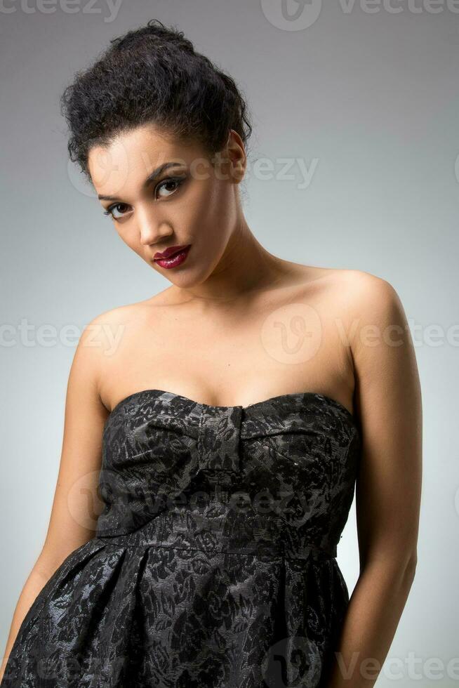 Portrait of beautiful brunette girl in the studio on a gray background in dress photo