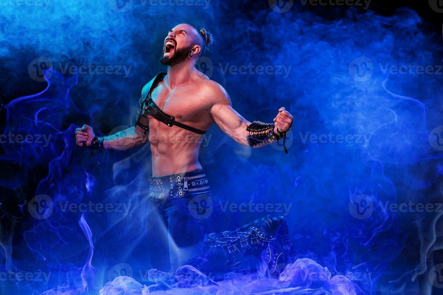 Handsome young sexy man with beautiful muscular chest in interesting costume on the scene photo
