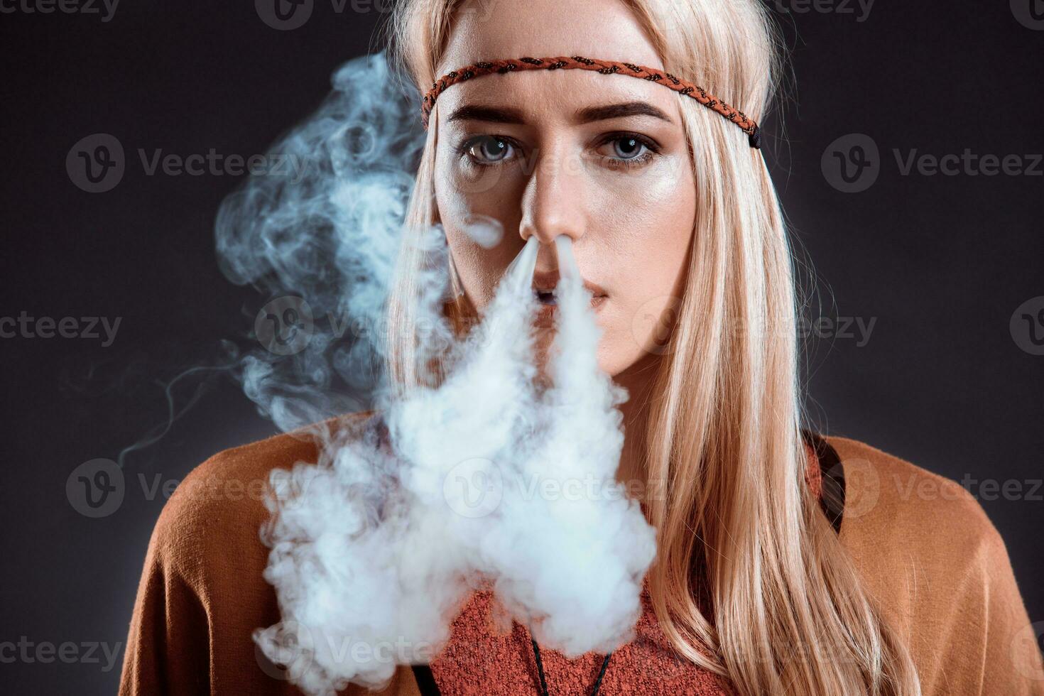 Young woman in the Boho style blowing smoke photo