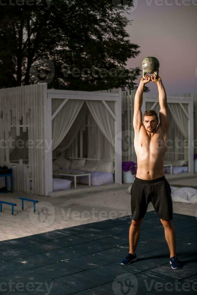 Muscular man working with weights at outdoor photo