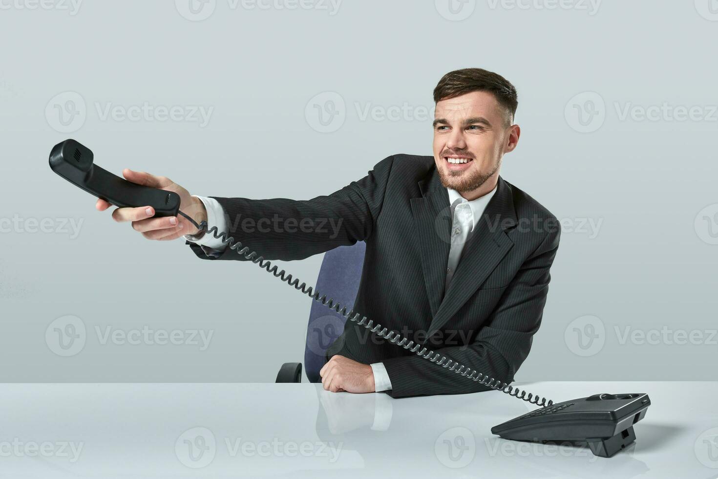 Portrait of attractive businessman holding telephone in his hand. This call is for you concept photo