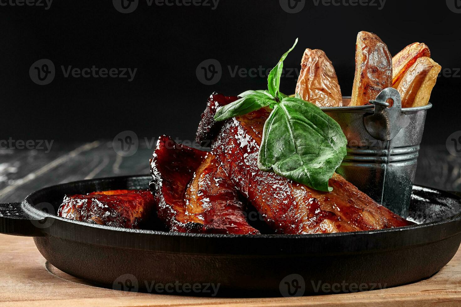 Grilled pork ribs in barbecue sauce with potato wedges photo