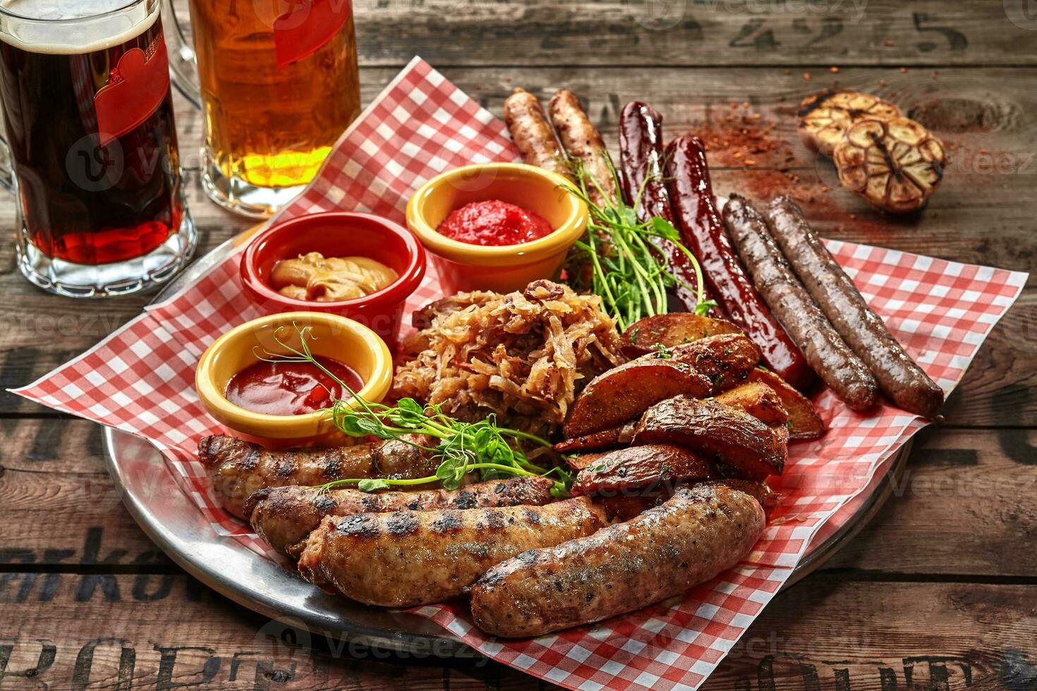 A la parrilla salchichas con patata porciones, estofado repollo y salsas como cerveza bocadillo foto