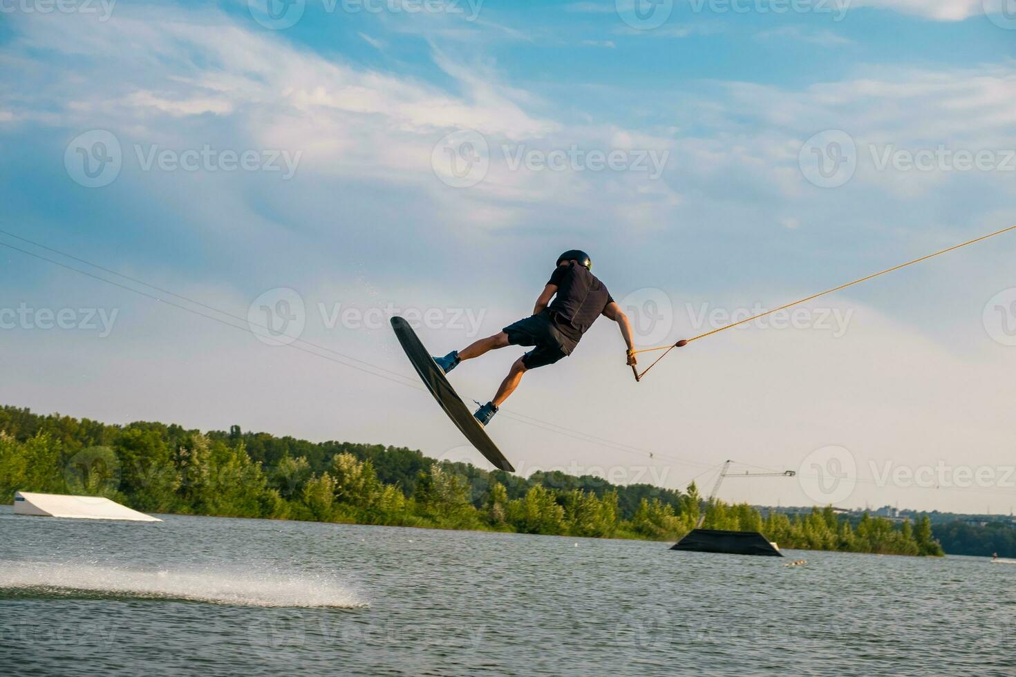 Young man jumping over water surface of river on wakeboard photo