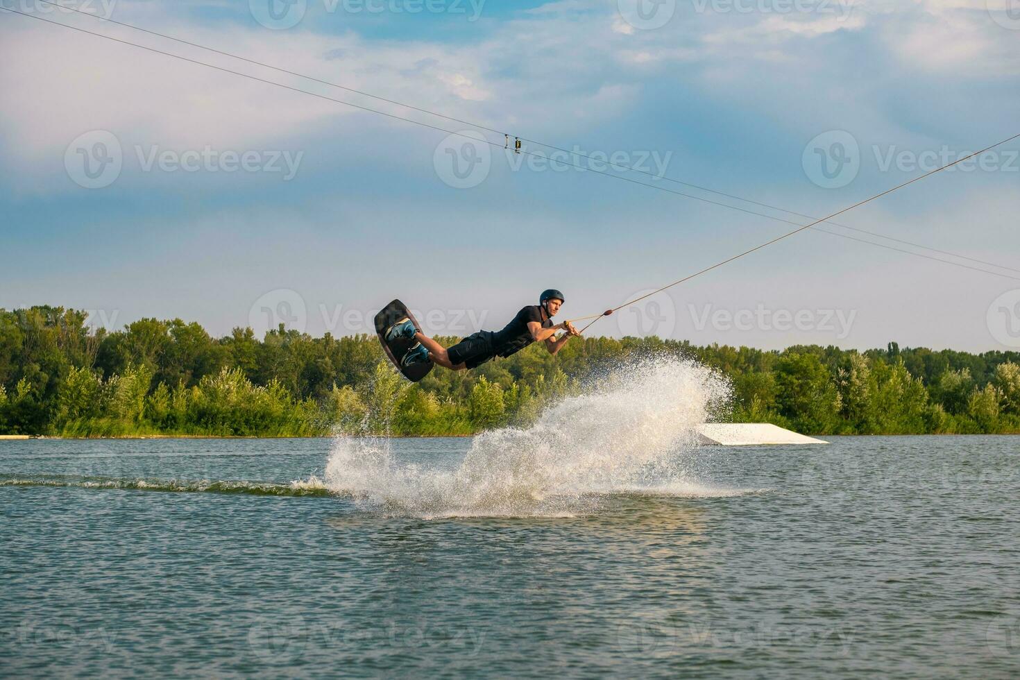 Man skilfully making tricks on wakeboard on summr day photo