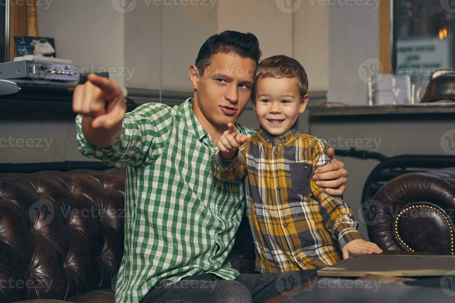 Young father and his stylish little son in the barbershop in the waiting room. photo