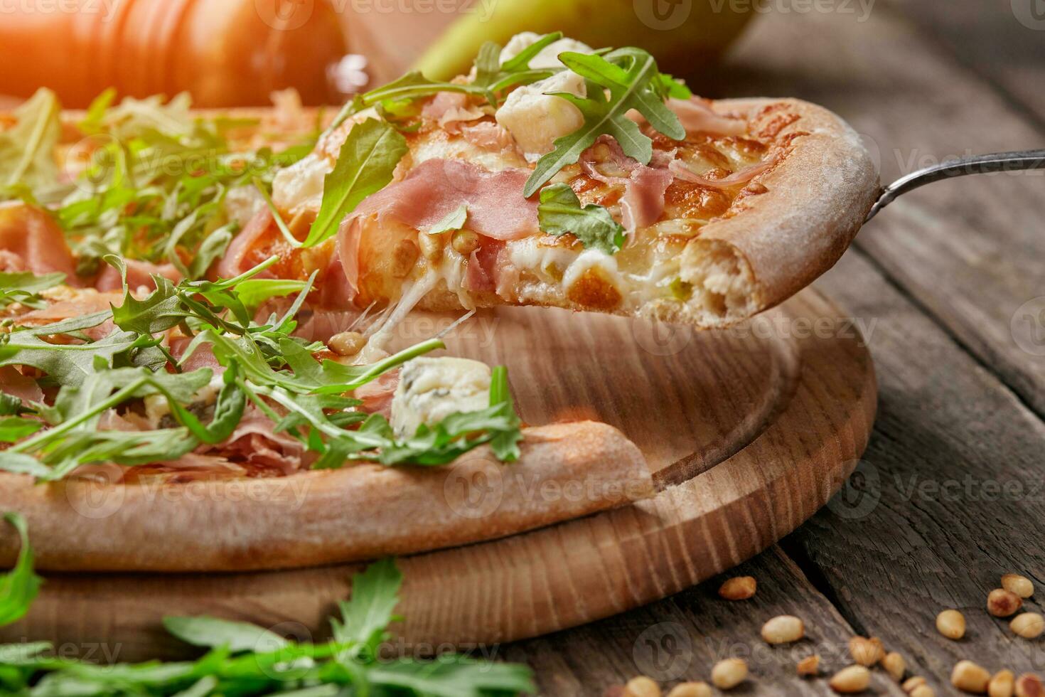 Slice of pizza with cured ham, blue cheese, pear, pine nuts, arugula photo