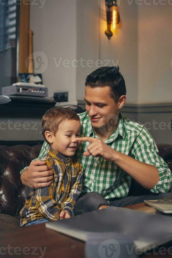 Young father and his stylish little son in the barbershop in the waiting room. photo