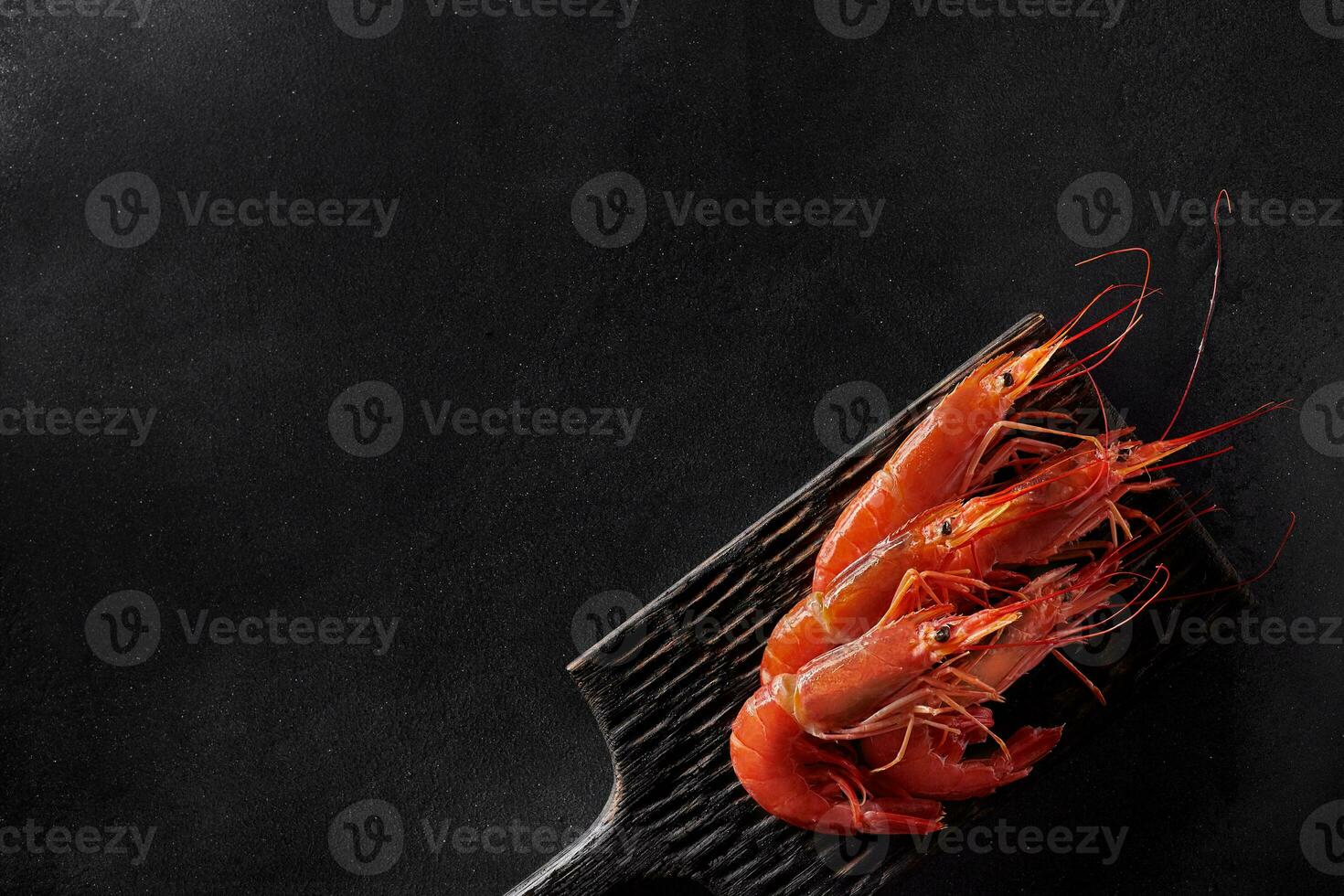 Top view of cooked whole prawns on black background photo