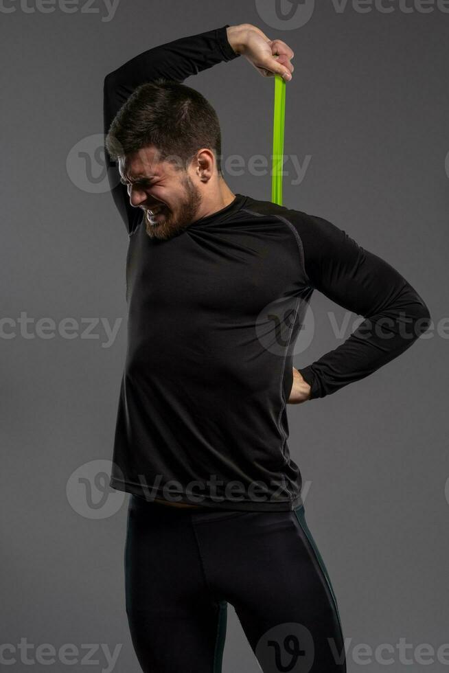 Man with tense facial expression performing resistance band workout photo