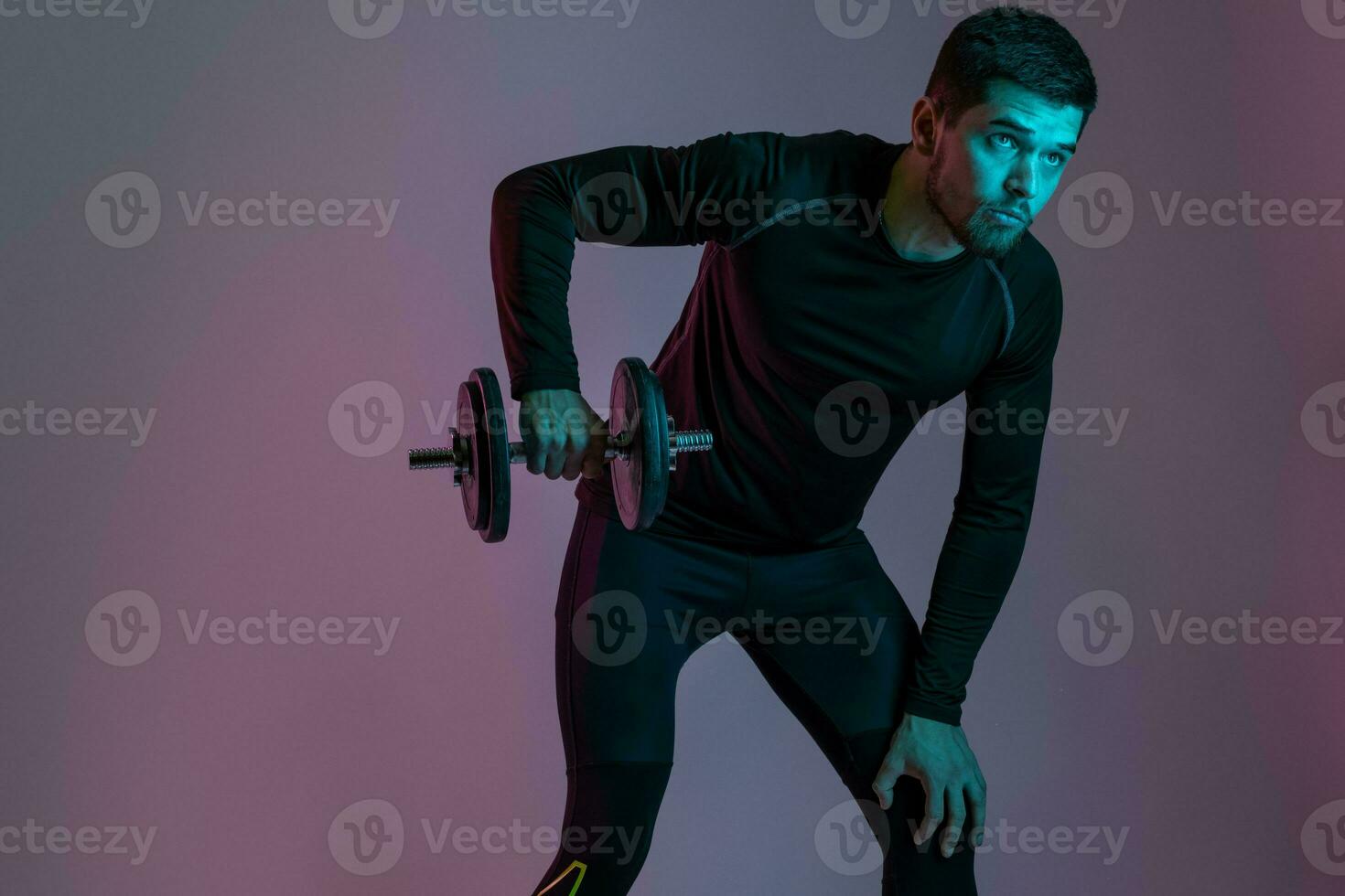 Athletic guy performing shoulder exercises with dumbbell photo