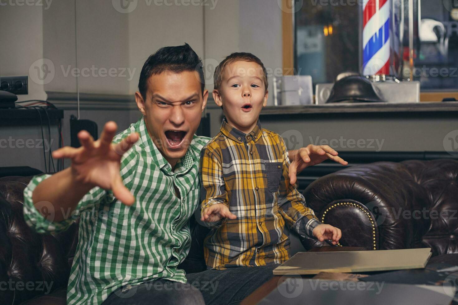 Young father and his stylish little son in the barbershop in the waiting room. photo