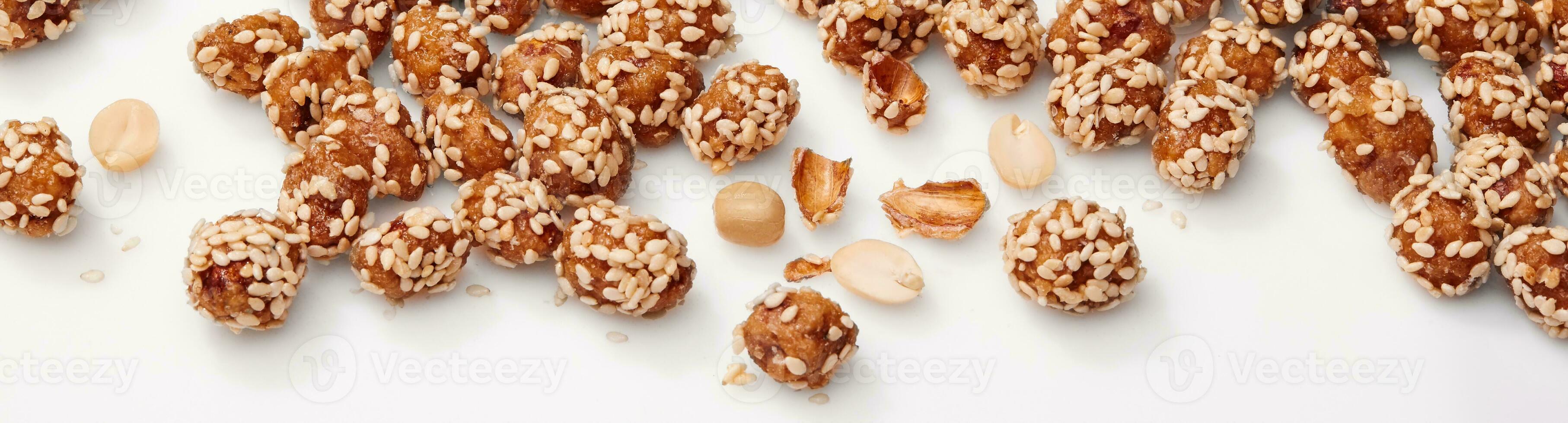 Candied peanuts in honey and sugar glaze with sesame on white photo