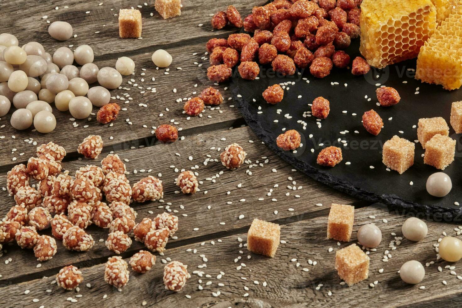 Candied peanuts on wooden table with honeycombs, sugar cubes and sesame photo