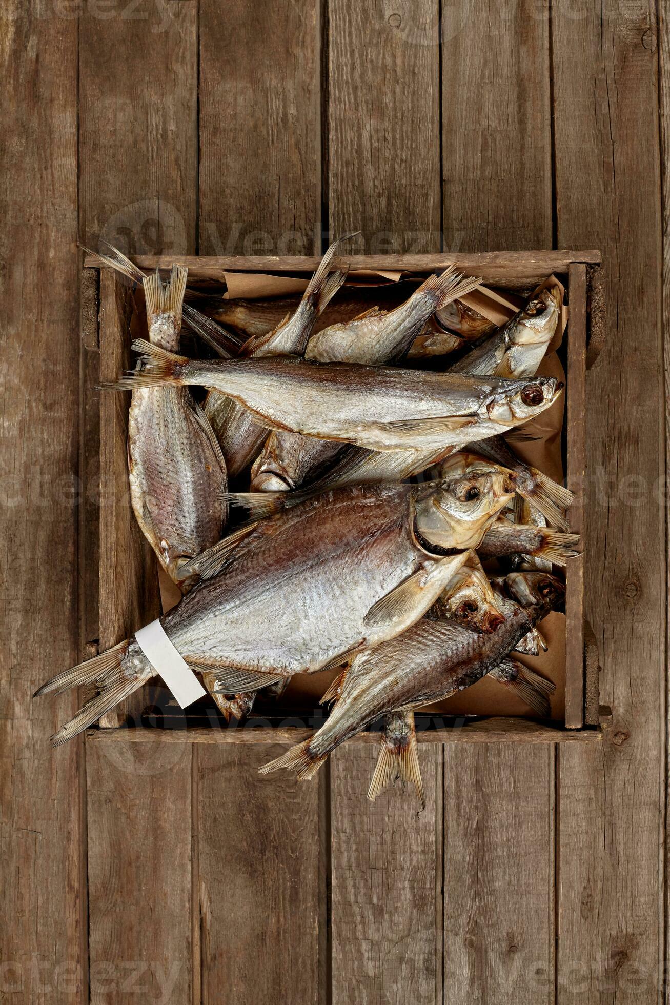 Crate with various sun-dried fish on wooden planks background