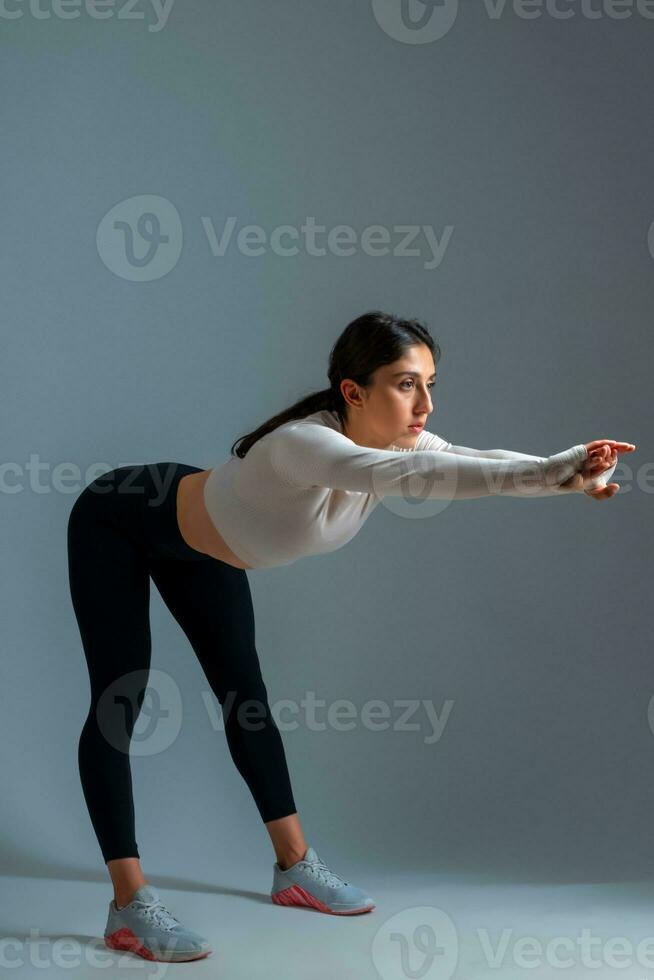 Girl bending body forward with outstretched arms on grey background photo
