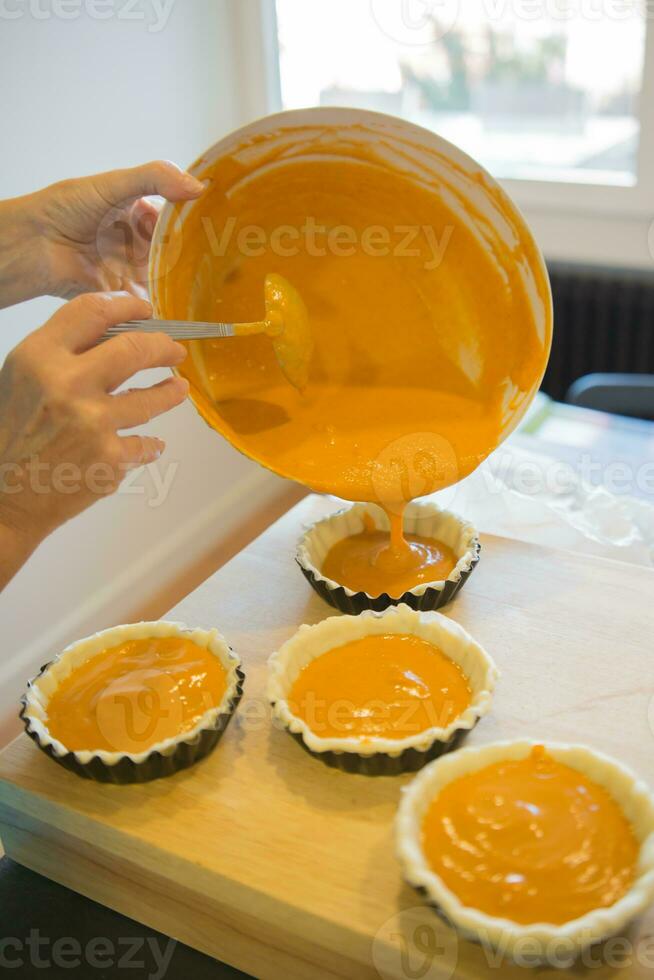 Close up of woman hands baking small pumpkin cakes photo
