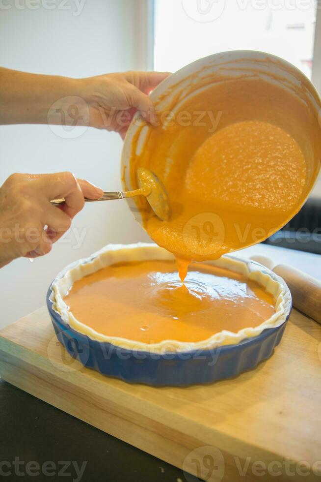 Close up of woman hands filling pumkin pie crust photo