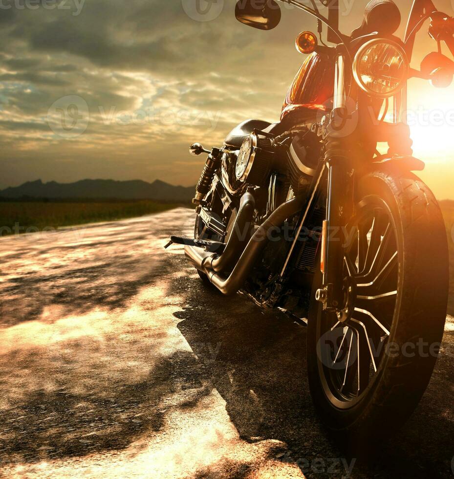 old retro motorcycle traveling on country road against beautiful light of sunset sky photo