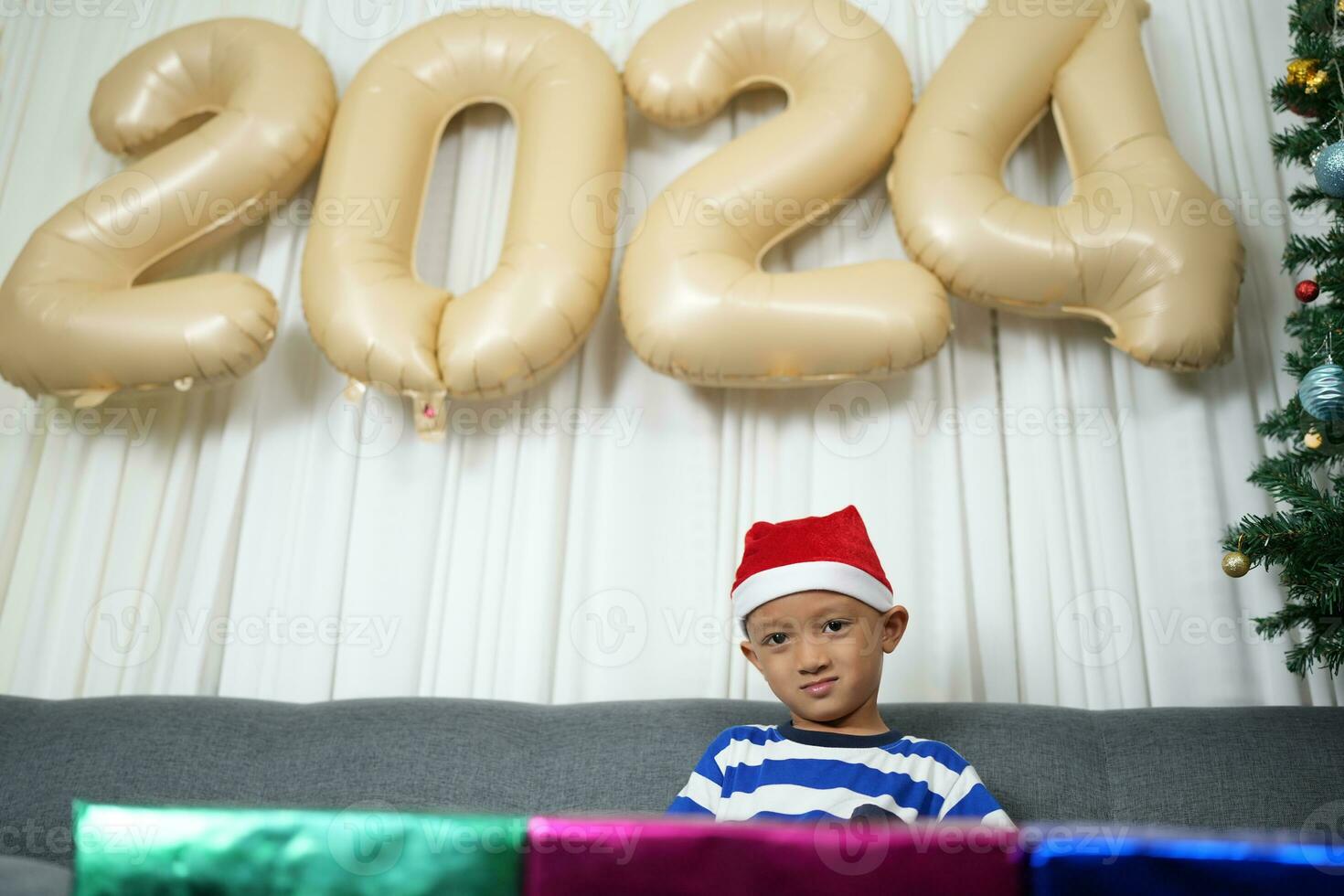 Merry Christmas 2024 concept A boy holding a gift box is happy to receive a present on Christmas Day. photo