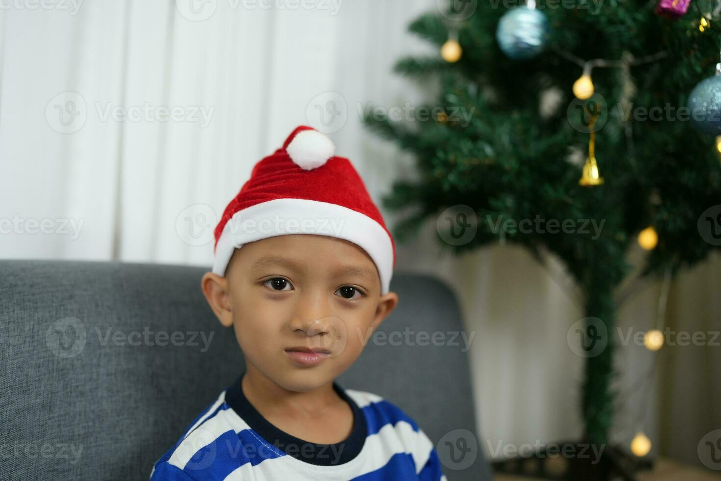 Merry Christmas 2024 concept Asian boy decorates Christmas tree with colorful Christmas balls. photo