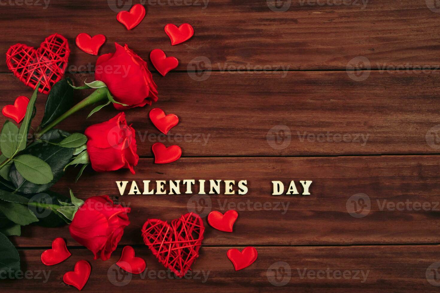 Red roses and hearts on a dark wooden background. Valentine's day postcard concept. photo