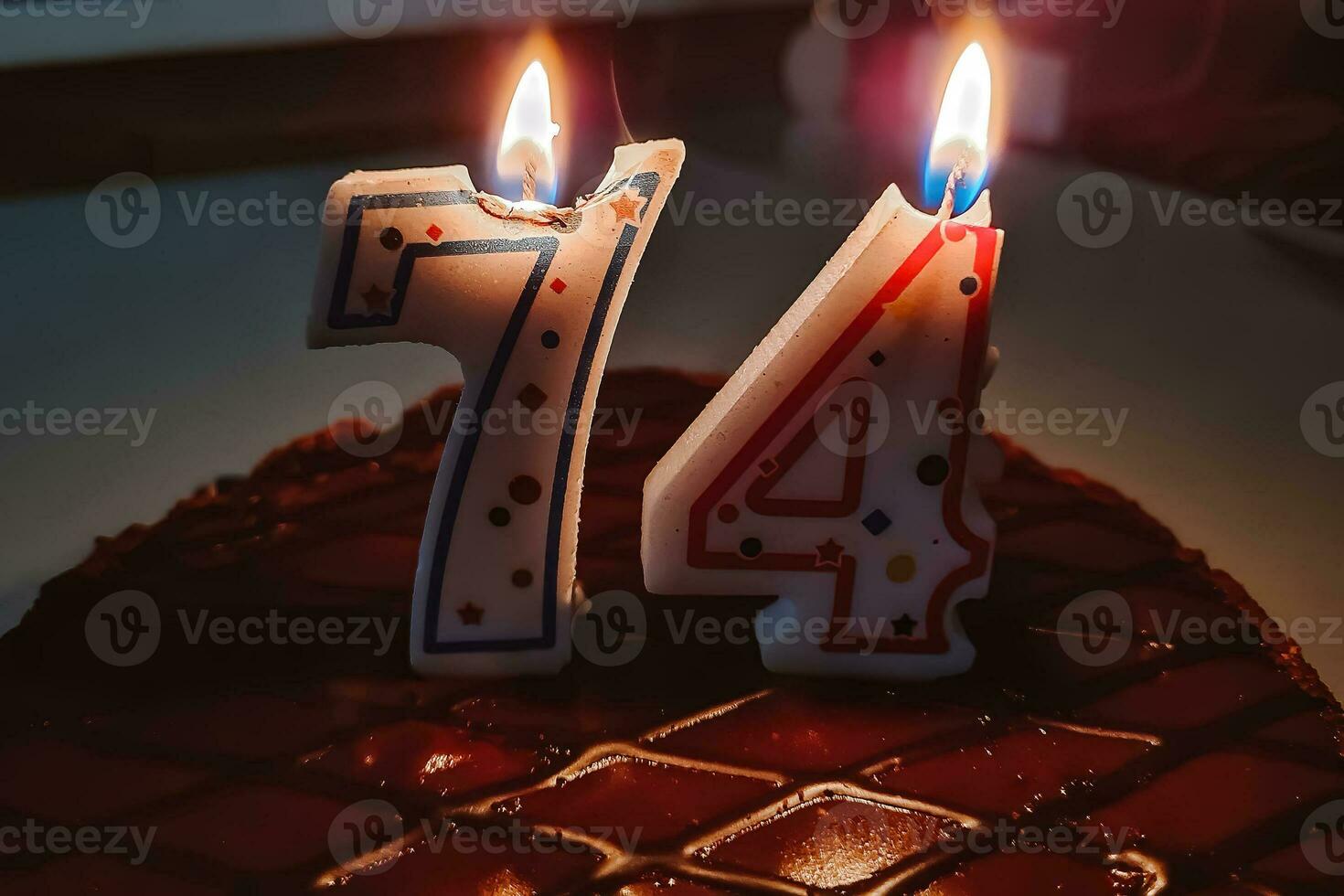 Festive candles on birthday cake. Celebrating an elderly persons 74th birthday. photo