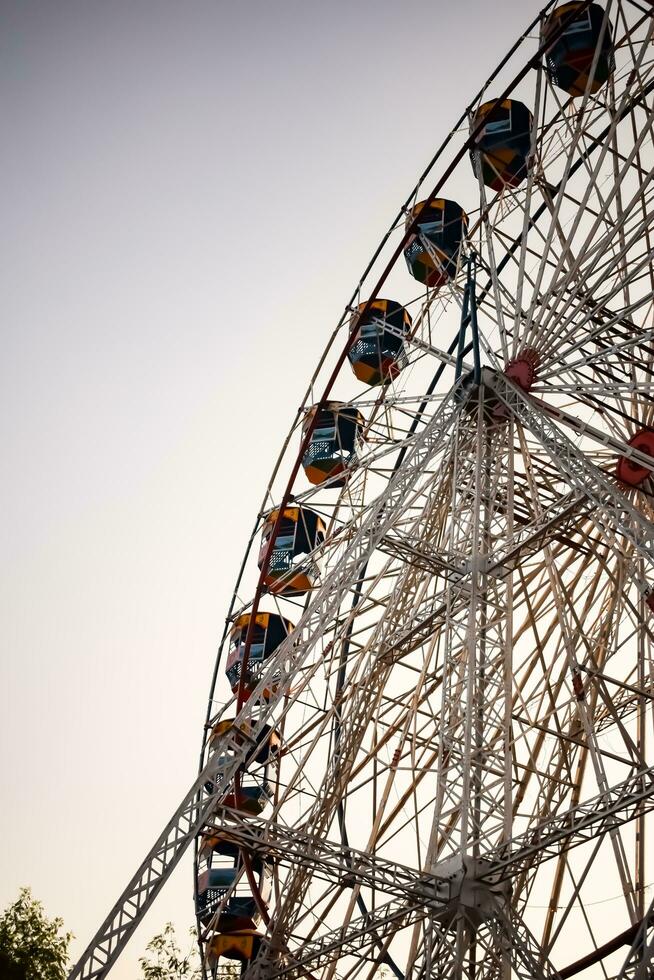 New Delhi, India - October 30 2023 - Closeup of multi-coloured Giant Wheel during Dussehra Mela in Delhi, India. Bottom view of Giant Wheel swing. Ferriswheel with colourful cabins during day time. photo