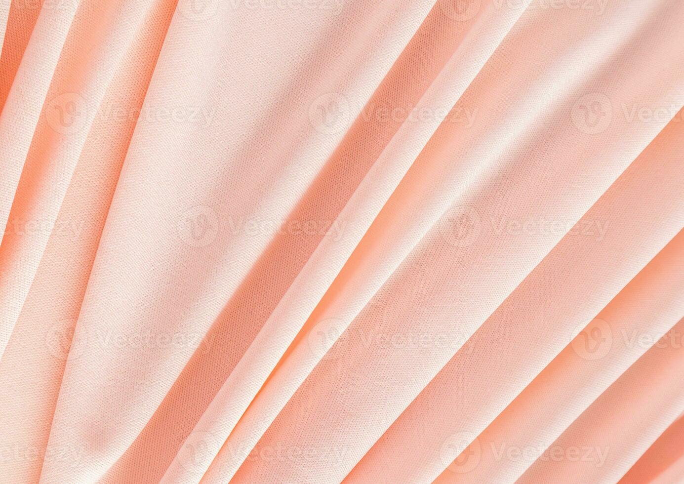 Elegant textile background in peach color with soft pleats. Festive background of the color of the year 2024 peach fuzz. A copy space. photo
