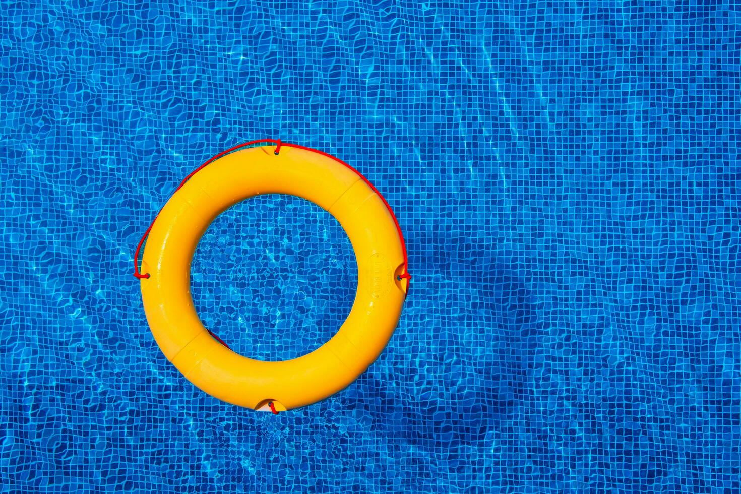 Top view of lifebuoy floating in blue swimming pool, soft focus. photo